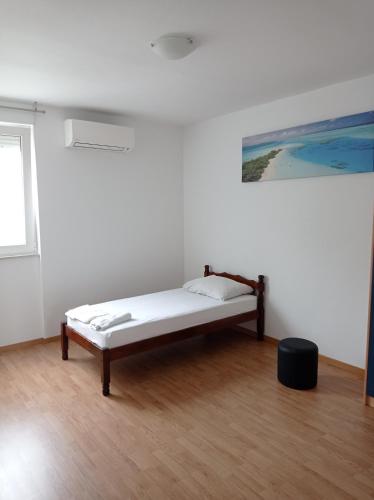 a bed in a white room with a painting on the wall at Nice and cozy two single bed room in Split