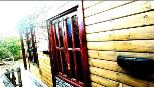ein Holzhaus mit einer roten Tür an der Seite in der Unterkunft Cabaña Onty in El Calafate