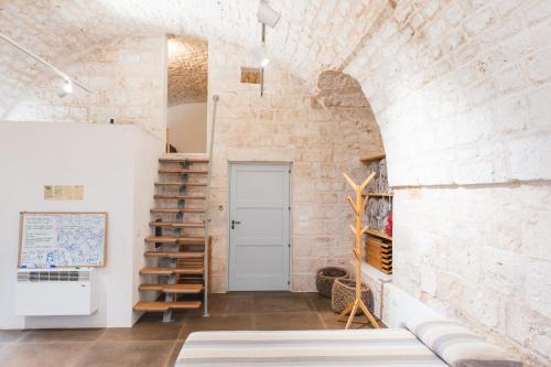 a room with a staircase and a brick wall at Ostello dei Giardini di Pomona in Cisternino