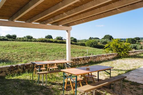 two picnic tables under a pergola in a field at Ostello dei Giardini di Pomona in Cisternino
