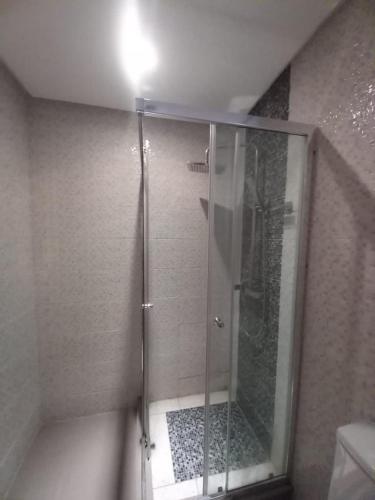 La salle de bains est pourvue d'une douche avec une porte en verre. dans l'établissement Bel Appartement à Mansbay, à Minaret de Mansuria