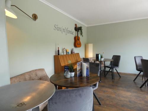a dining room with a table and a guitar on the wall at NordseeResort Hotel & Suite Arche Noah in Horumersiel