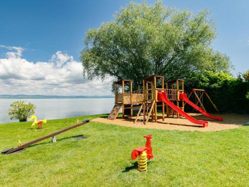 a playground with a slide in the grass next to the water at Apartment Figo by Interhome in Balatonőszöd