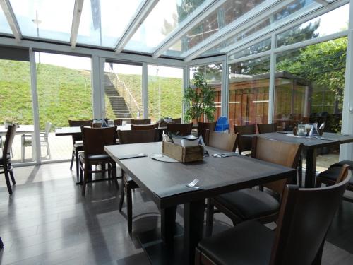 uma sala de jantar com mesas, cadeiras e janelas em NordseeResort Hotel & Suite Arche Noah em Horumersiel