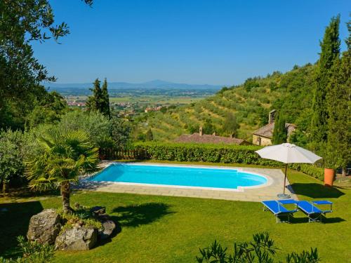 a pool in a yard with two chairs and an umbrella at Holiday Home Il Farinaio by Interhome in Cortona