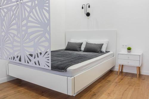 een bed in een witte kamer met een muur bij Lux Apartment Umai in Astana