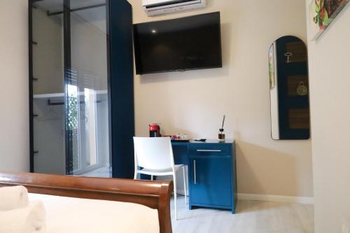 a bedroom with a blue desk and a tv on the wall at Hermitage Suites in Sassari