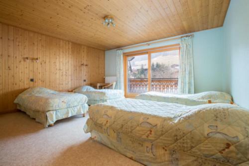 a bedroom with three beds and a window at Chalet Poupette in Morzine