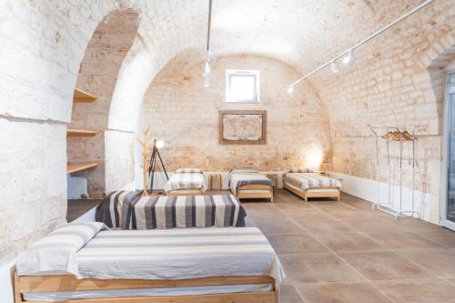 a room with four beds and a brick wall at Ostello dei Giardini di Pomona in Cisternino