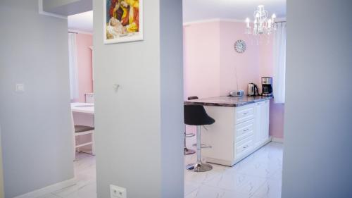 a white kitchen with a table and a stool at Dom Jeziorna Perla in Ośno Lubuskie