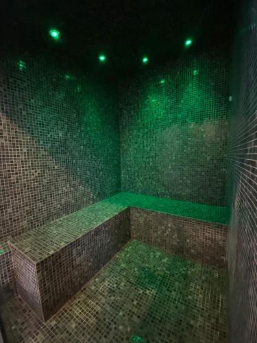 a bathroom with green lights on a tiled wall at Villa Rey Spa & Hotel in Vila de Rei