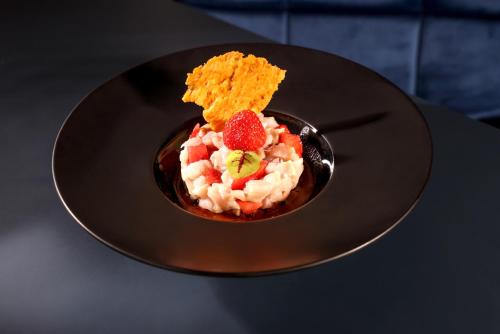 a black plate with a dessert on a table at Logis Hôtel Restaurant Europa in Maussac