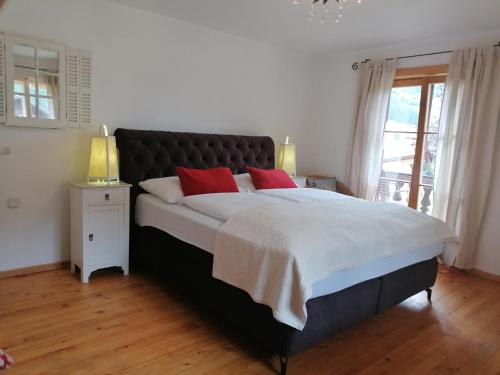 a bedroom with a large bed with two red pillows at Schlosswirt Chalets & Apartments in Großkirchheim