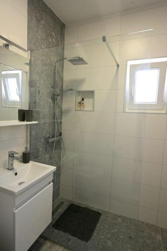 a white bathroom with a shower and a sink at House La Vista Hvar in Hvar