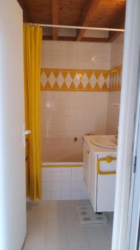 a bathroom with a yellow shower curtain and a sink at Pousada Bertin in Chatou