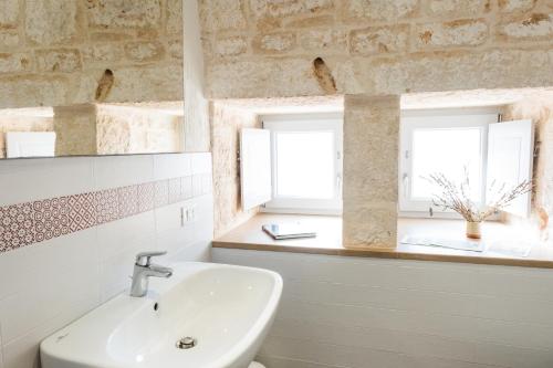 baño con lavabo y 2 ventanas en Ostello dei Giardini di Pomona, en Cisternino