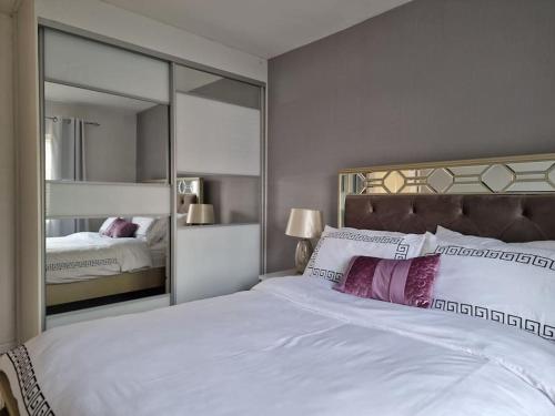 a bedroom with a large white bed with a large mirror at Silverstone Stays in Wootton