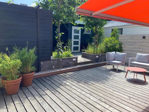 a patio with an orange umbrella and a chair on a deck at Unieke woonark met privétuin en free parking. in Rotterdam