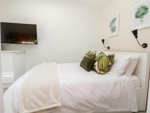 un letto bianco con cuscini e una TV a parete di Garden Studio a Wallasey