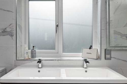 a white bathroom with two sinks and a window at Clydfan in Holyhead