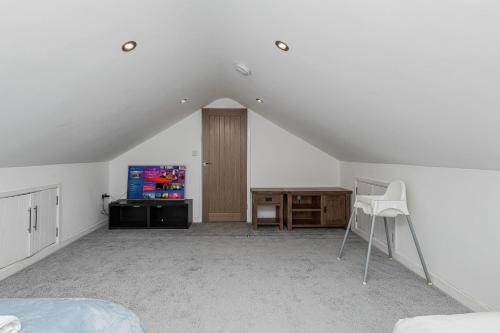 an attic room with a bed and a tv at Clydfan in Holyhead