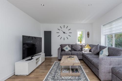 a living room with a couch and a clock on the wall at Clydfan in Holyhead