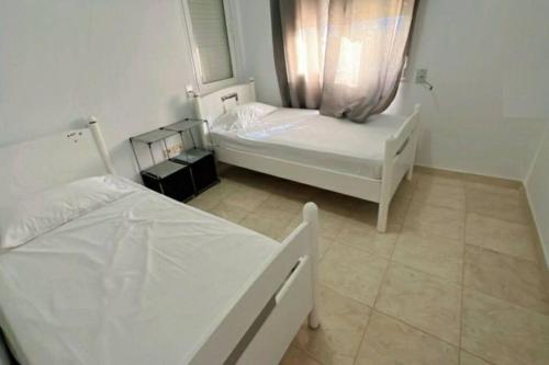 um quarto com 2 camas e uma janela em Chez Sarah em Beni Khiar