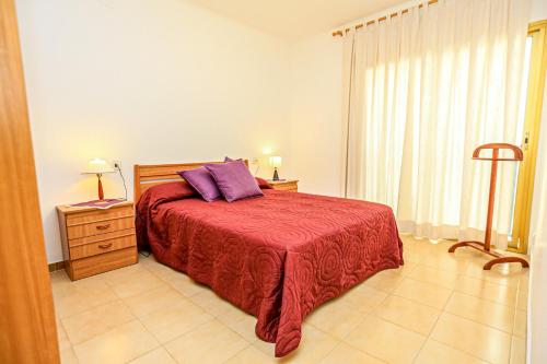 - une chambre avec un lit doté d'un couvre-lit rouge et d'oreillers violets dans l'établissement Pins i Mar - ONLY FAMILIES, à Cambrils