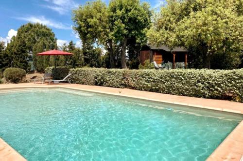 een zwembad in een tuin met een rode parasol bij Eole, villa d'architecte, vue mer, piscine in Bormes-les-Mimosas