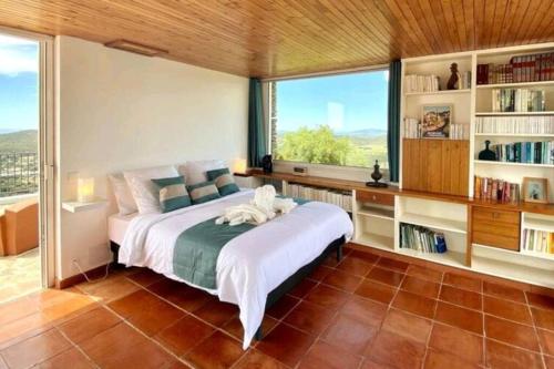 a bedroom with a large bed and a large window at Eole, villa d'architecte, vue mer, piscine in Bormes-les-Mimosas