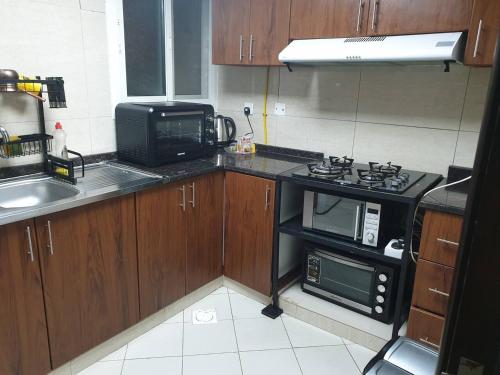 eine kleine Küche mit einem Herd und einer Mikrowelle in der Unterkunft One BHK in Ajman 