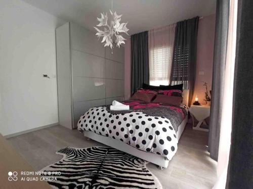 1 dormitorio con 1 cama con lunares blancos y negros en Villa SUN en Ashqelon