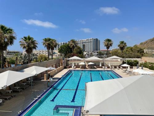 una piscina con ombrelloni bianchi e un resort di אוקיינוס במרינה מלון דירות בעלים פרטיים עם נוף לים מרפסת אחד עד שני חדרי שינה וסלון a Herzliya B