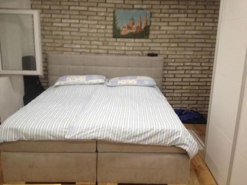 un letto in una camera da letto con muro di mattoni di Kamena Kuca a Crikvenica