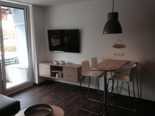 a living room with a table and chairs and a tv at Apartmenthaus Seetempel in Scharbeutz