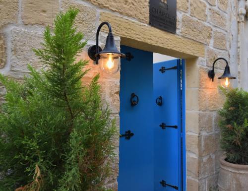 a blue door with lights attached to a stone building at Chapel 5 Boutique Suites B&B in Naxxar