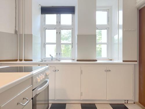 コペンハーゲンにあるCopenhagen 2 Bedroom Apartmentの白いキャビネットと2つの窓付きのキッチン