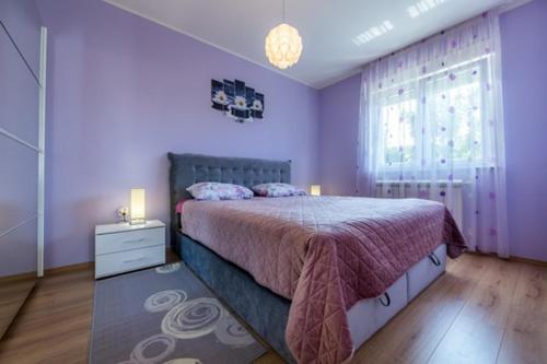 Dormitorio púrpura con cama y ventana en KARLO, en Čavle