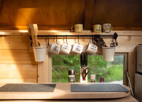 a kitchen with cups and utensils hanging from a wall at Troll House Eco-Cottage, Nuuksio for Nature lovers, Petfriendly in Espoo