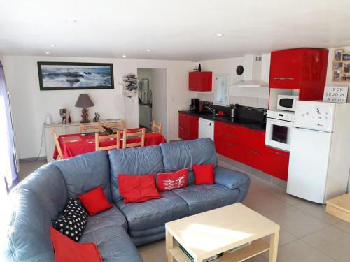 sala de estar con sofá y cocina con armarios rojos. en Gîte Avec Spa et Sauna Privatifs, en Poullaouen