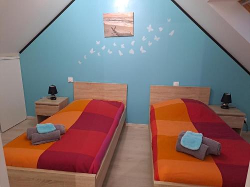 2 camas en una habitación con paredes azules en Gîte Avec Spa et Sauna Privatifs, en Poullaouen