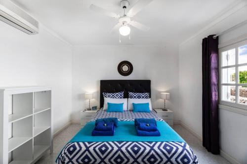 a bedroom with a large bed with blue pillows at Caserones 04 in Puerto del Carmen