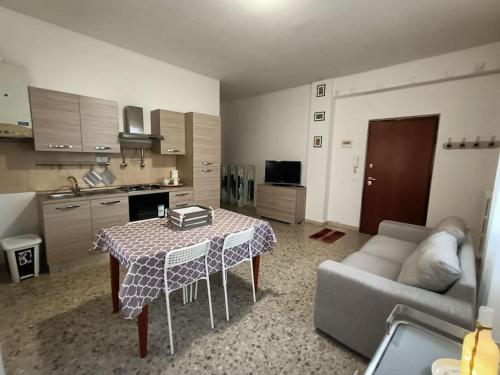 cocina y sala de estar con mesa y sofá. en Appartamento luminoso in zona centrale, en Montesilvano
