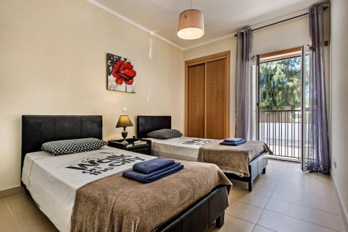 two beds in a room with a balcony at Formosa Cabanas Beach in Cabanas de Tavira