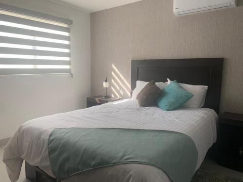 a bedroom with a large bed with blue pillows at San Miguel Cabañas in Valle de Guadalupe