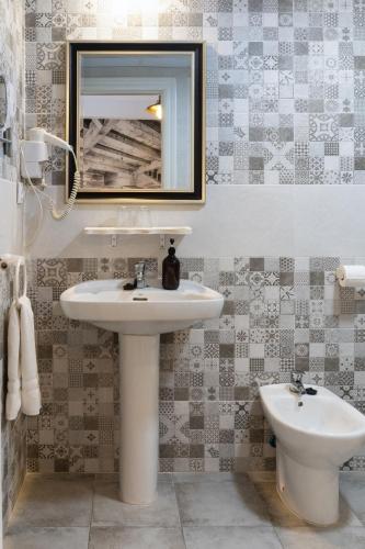 a bathroom with a sink and a mirror and a toilet at Hotel Alquimia Cadiz in Cádiz