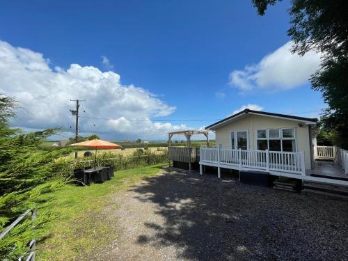 a small white house with an umbrella and a field at Mountain View Lodge in Whitland