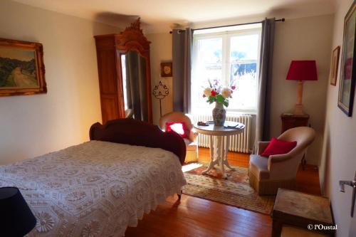Sainte-Eulalie-dʼOltにあるL'Oustalのベッドルーム1室(ベッド1台、テーブル、窓付)