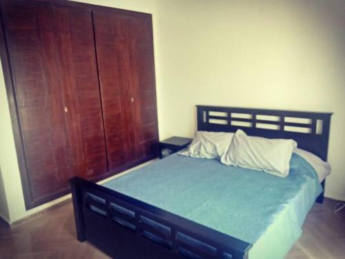 Schlafzimmer mit einem großen Bett und einer Holztür in der Unterkunft Appartement à 2 minutes de la plage Skhirat in Skhirat