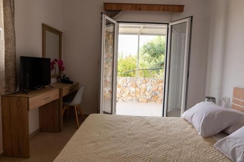 Schlafzimmer mit einem Bett, einem Schreibtisch und einem Fenster in der Unterkunft Zografia - Charming House near the coast in Kos-Stadt